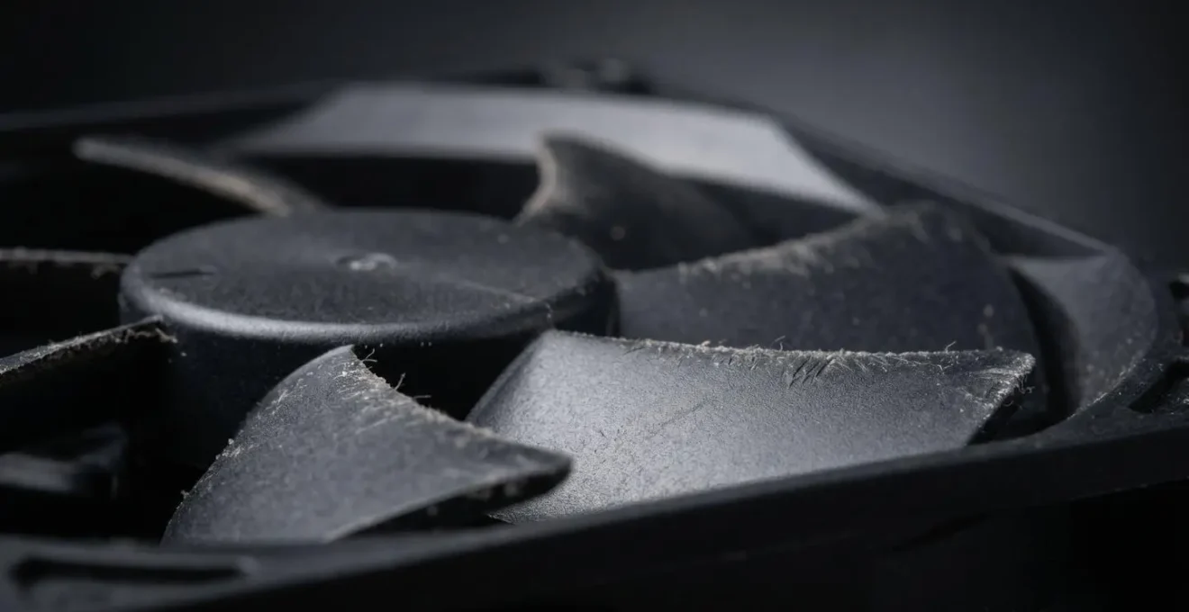 Gros plan sur ventilateur d'alimentation PC montrant accumulation de poussière et signes d'usure