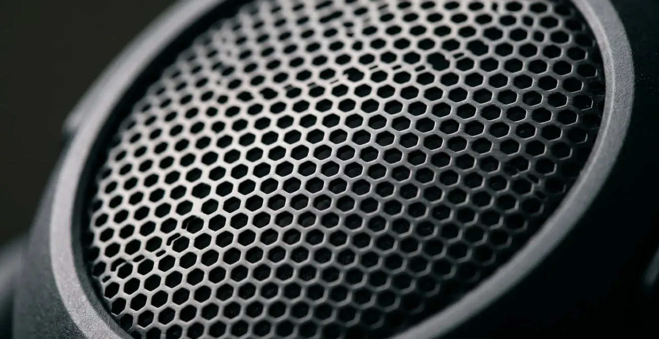 Gros plan macro sur les perforations acoustiques d'un casque semi-ouvert montrant la structure interne