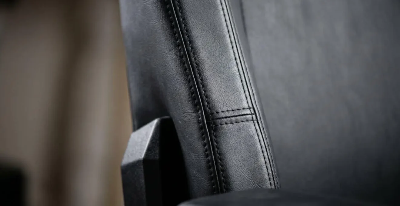 Vue rapprochée des structures latérales rigides d'une chaise gaming illustrant les contraintes imposées au torse et aux épaules