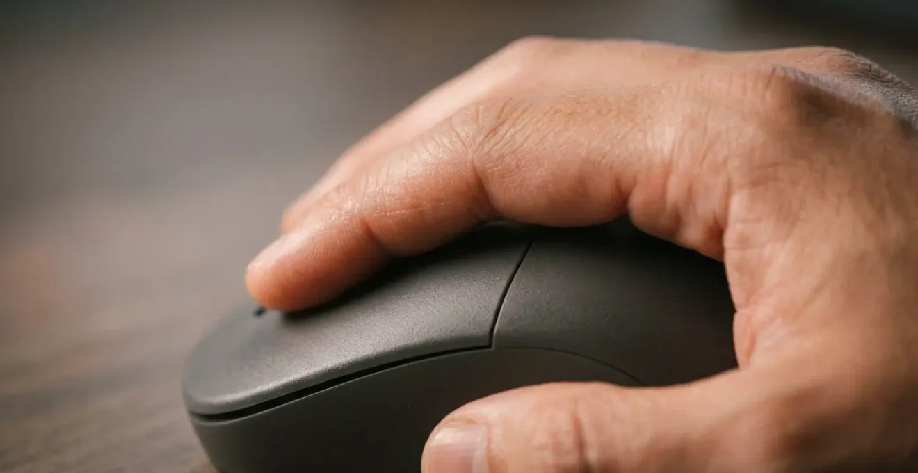Gros plan macro d'une main détendue posée sur une souris ergonomique, illustrant la stabilité naturelle et l'absence de crispation